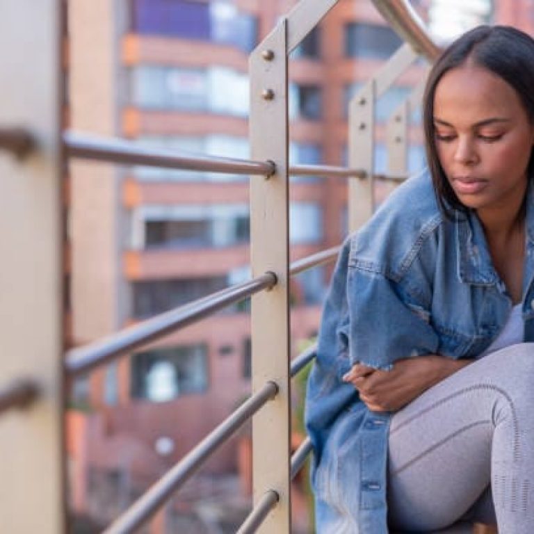 Beautiful Latin brunette woman from Bogota Colombia between 30 and 39 years old, sitting on her balcony with her arms crossed very sad for all the time she has locked up at home