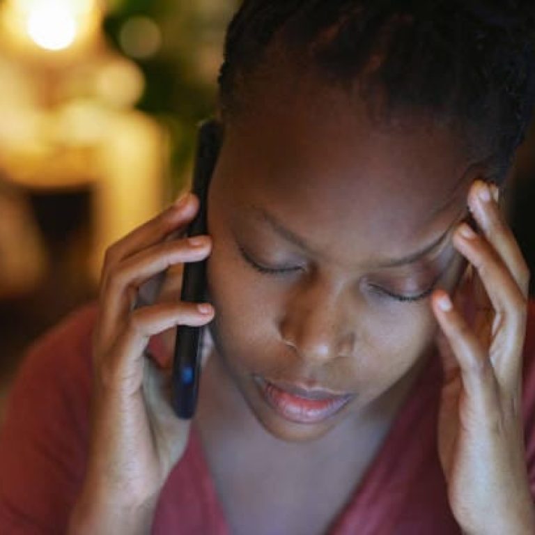 Shot of a young woman looking stressed out while talking on a cellphone at night