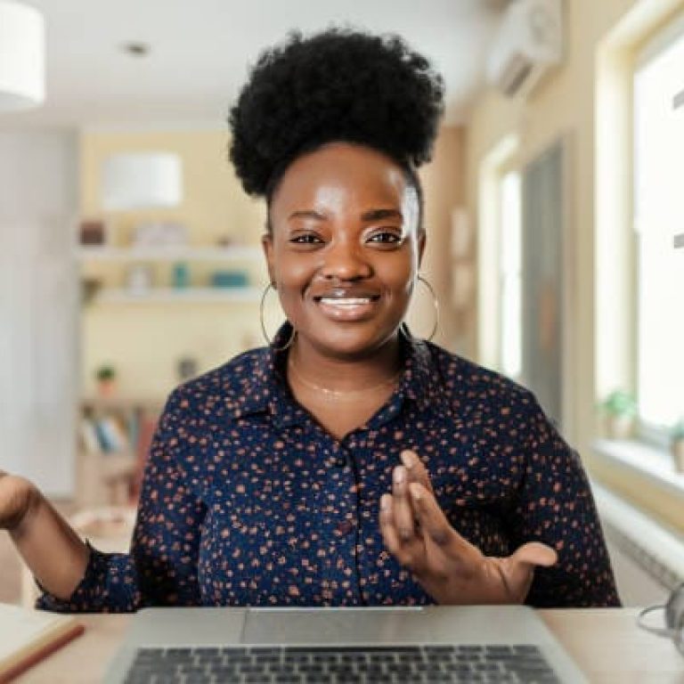 Happy Young African American Woman Blogger Applicant Teacher Sit at Home Office Look at Camera Doing Online Job Interview During Video Chat Conference Call Record Vlog Teaching on Webinar in App, Webcam View