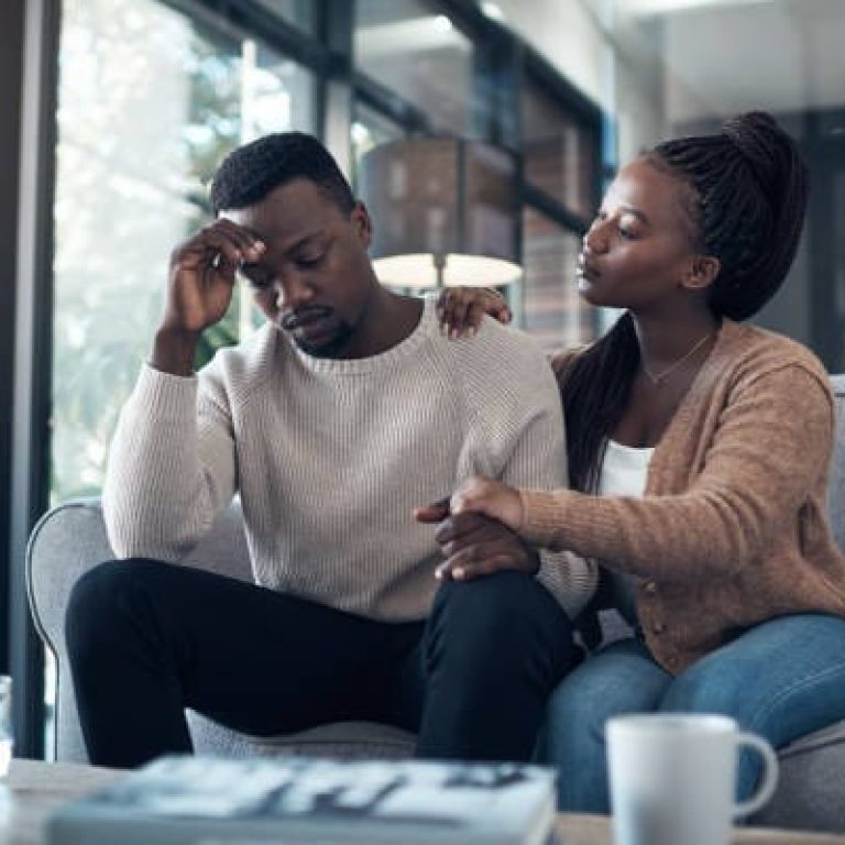 Cropped shot of a handsome young man sitting in his living room and stressing while his girlfriend comforts him