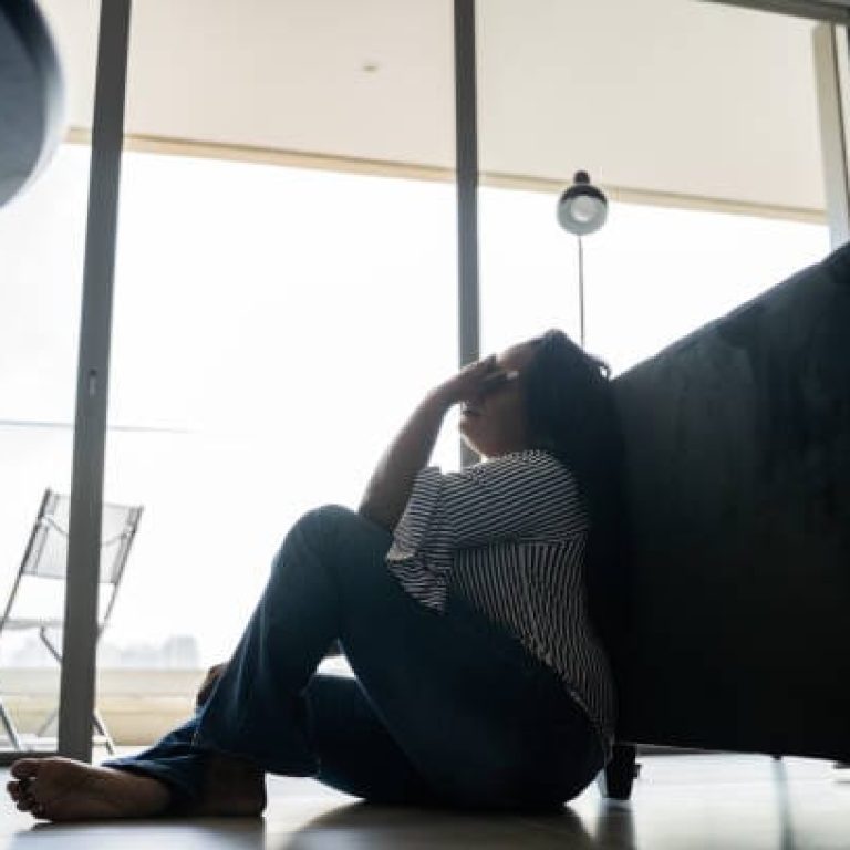 Depressed mature woman sitting on the ground at home