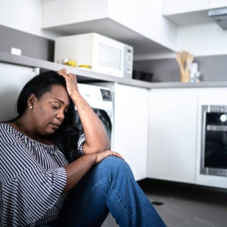 Depressed mature woman sitting on the ground at home