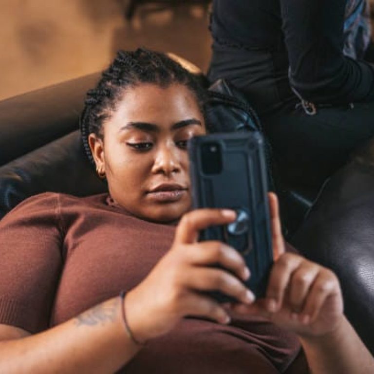 Teenage girl relaxing on the coach on mobile phone.
