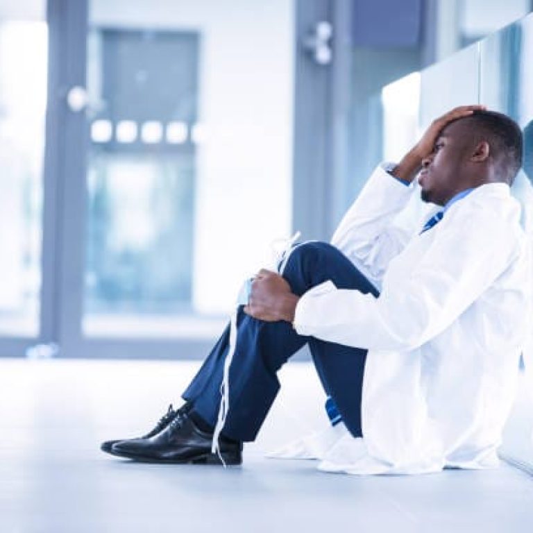 Worried doctor sitting on floor in hospital
