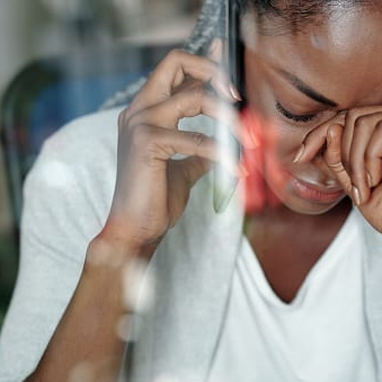 Young Black woman crying when receiving bad news on the phone