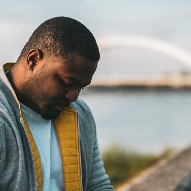 Depressed black man sitting outdoor.