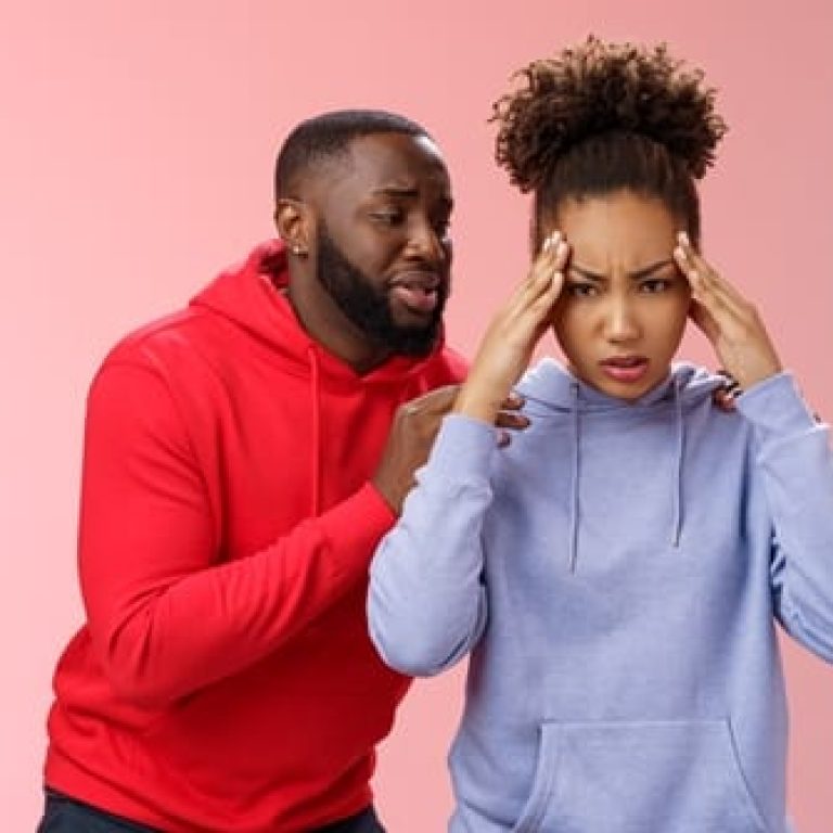 African american couple have fight arguing woman fed up cannot hear apologize anymore hold hands temples frowning pressured annoyed man begging forgiveness behind back supplicating say sorry.