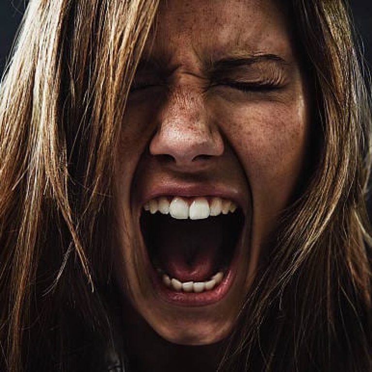A young woman screaming uncontrollably while isolated on a YELLING CRY