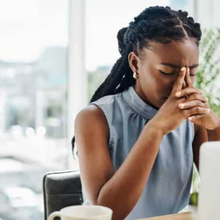 Stressed black businesswoman working on a laptop in an office alone